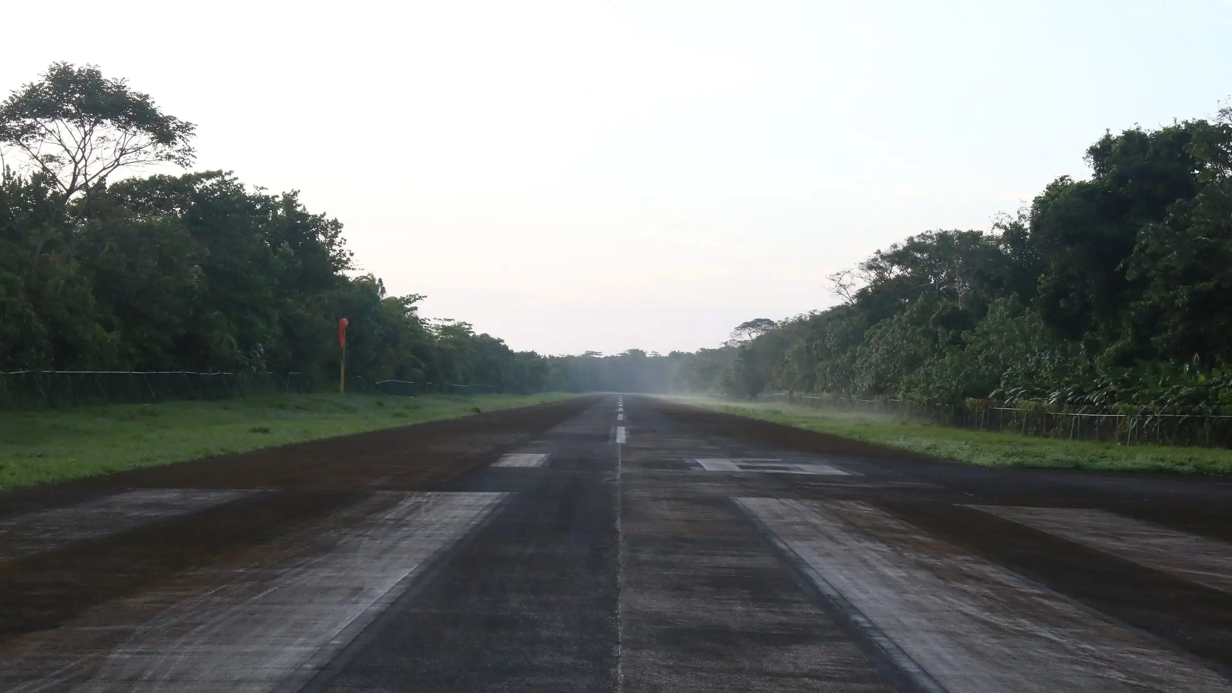 A remote unpaved airstrip cut through dense forest at first light