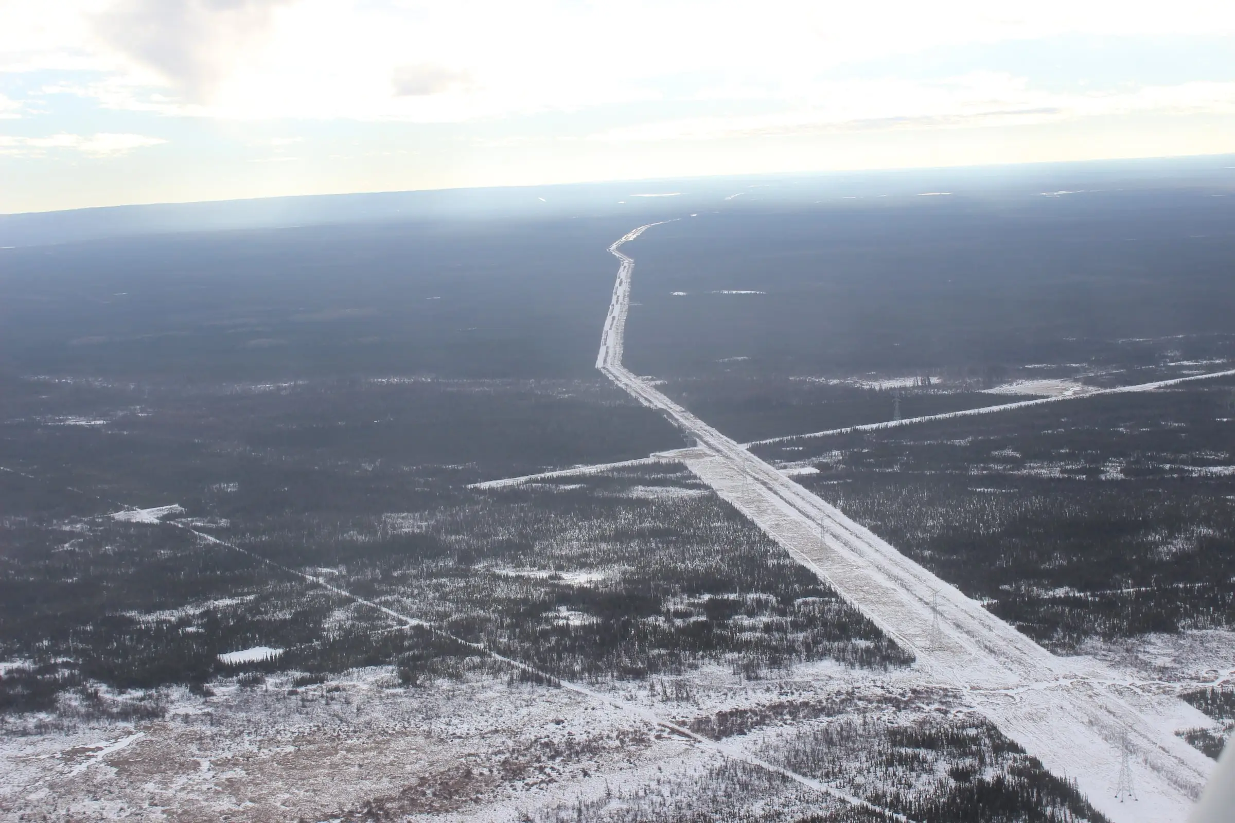 A pipeline and utility right-of-way cut through forest, seen from the air