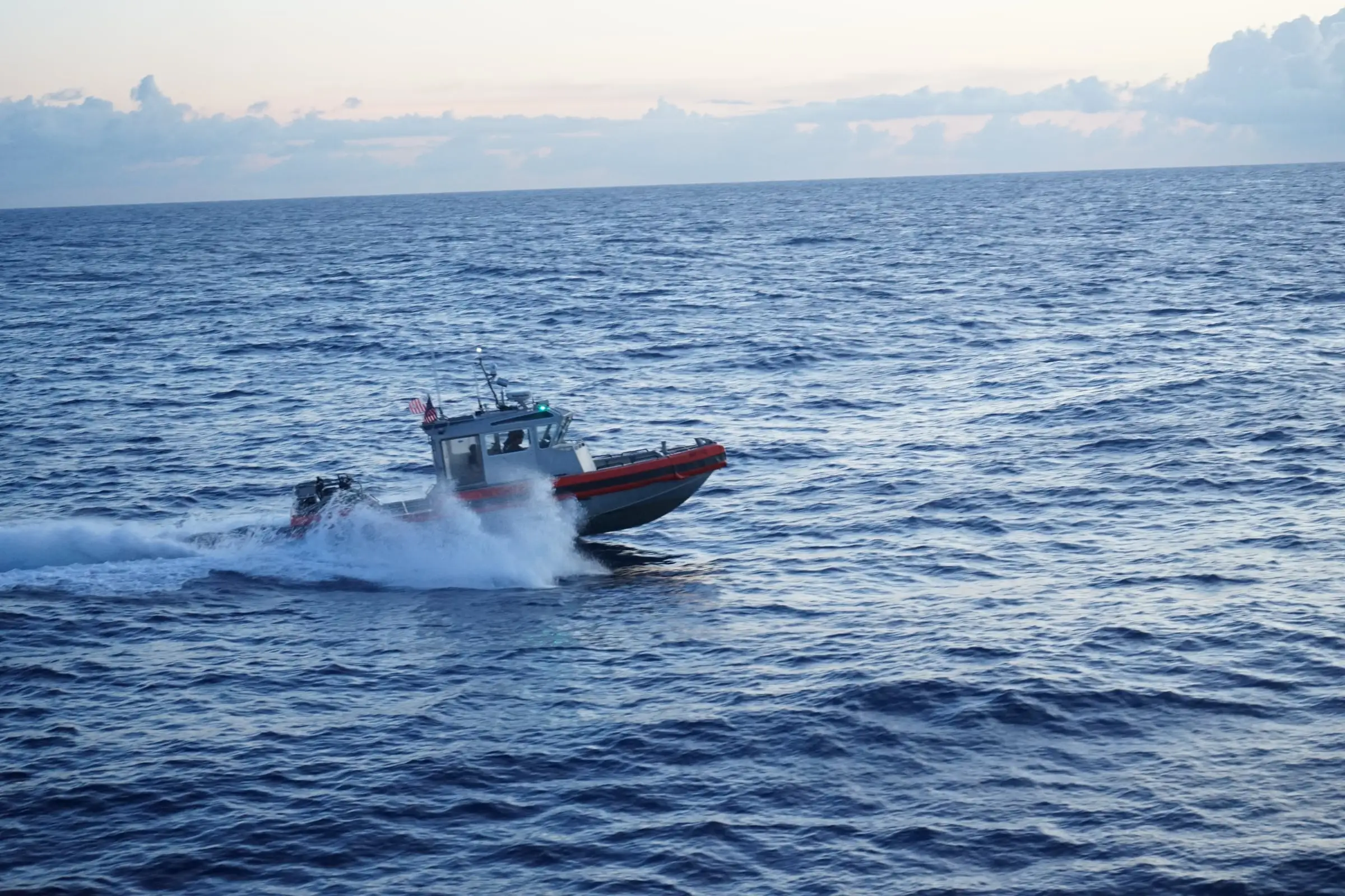 An interceptor craft at speed on open water at first light