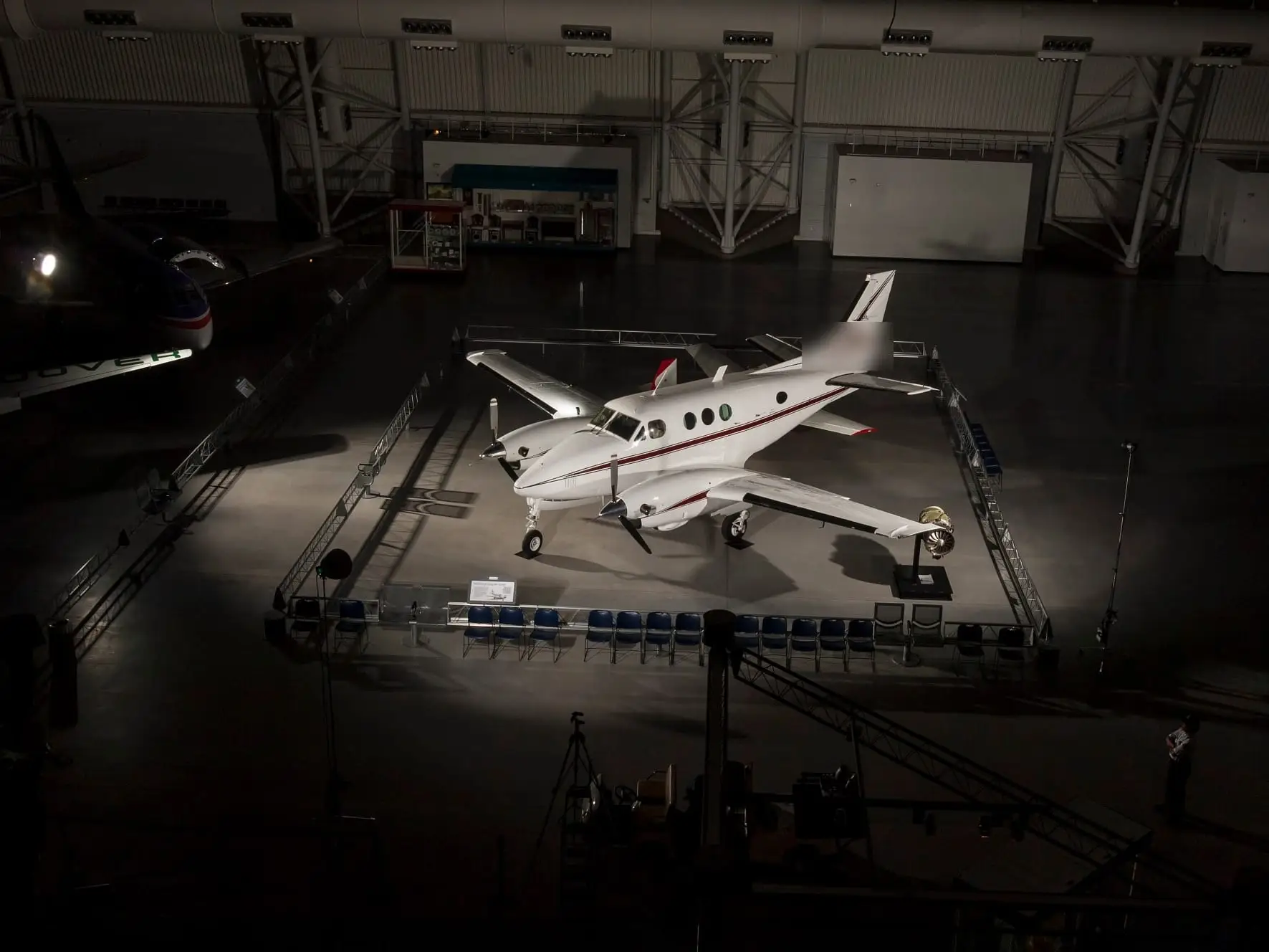 A twin-turboprop lit in a darkened hangar