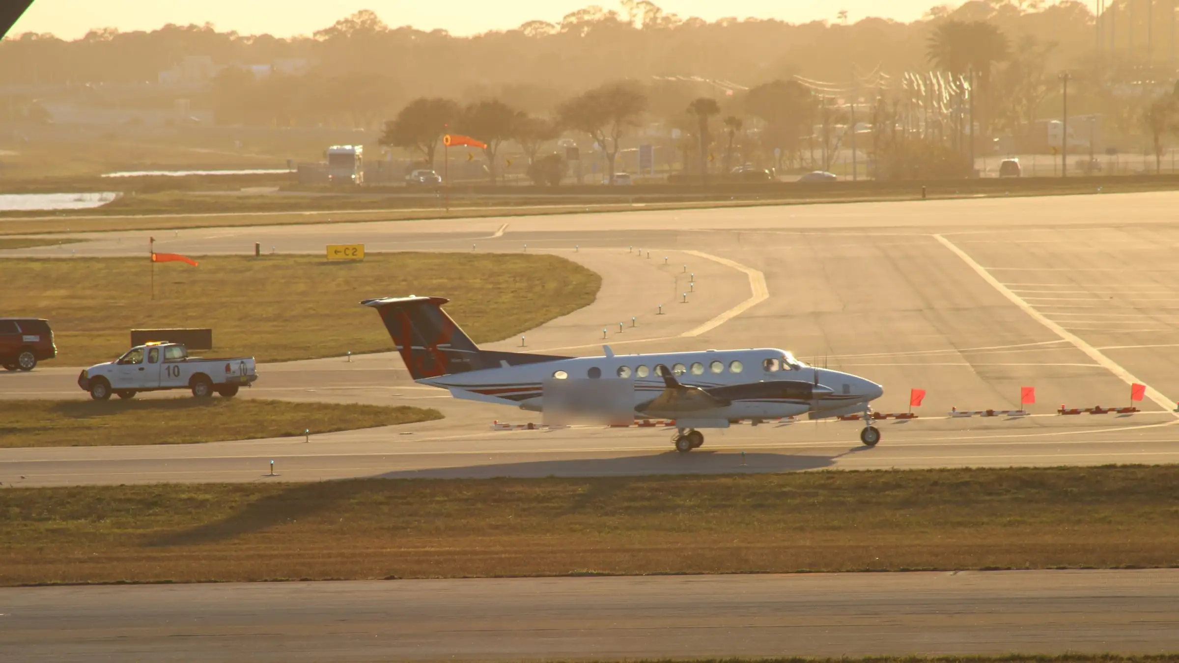 A twin-turboprop holding short on a taxiway in low winter light