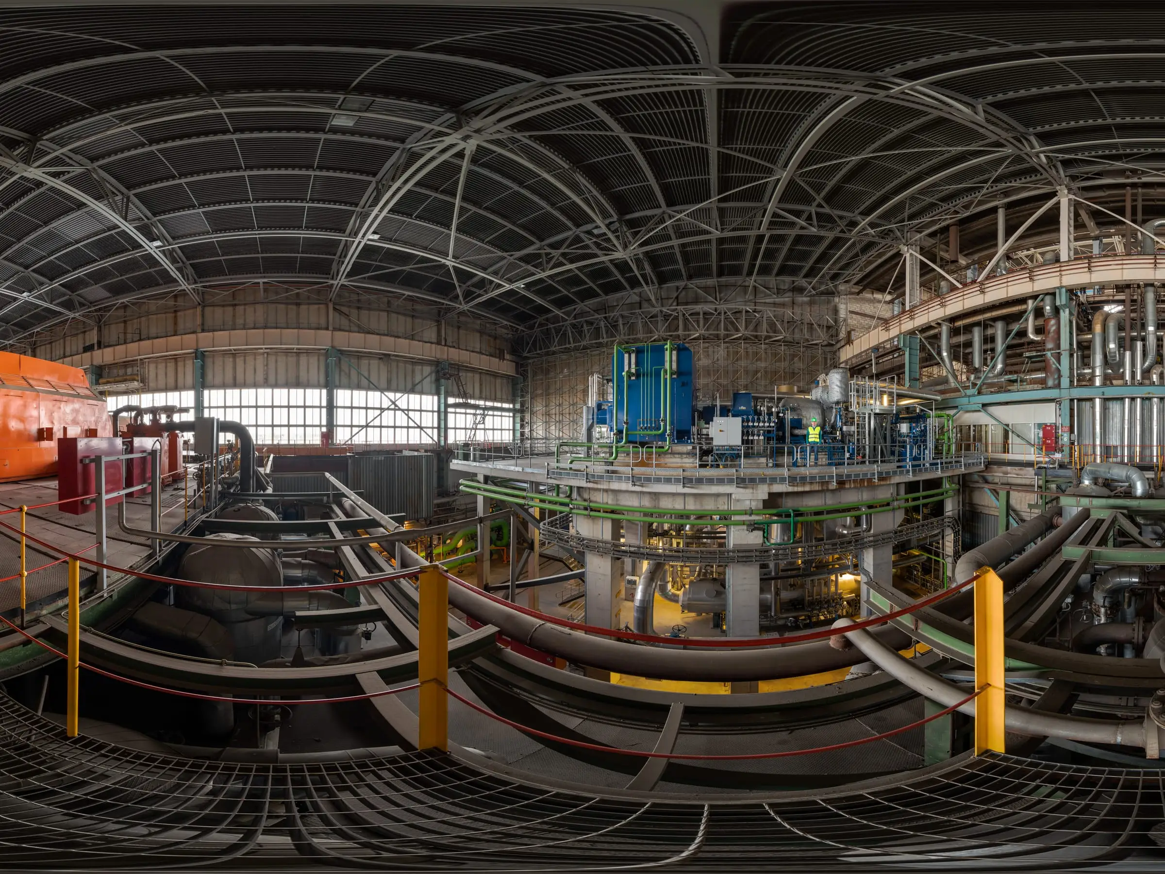 The turbine hall of a power plant, generator casing and pipework running the length of the floor