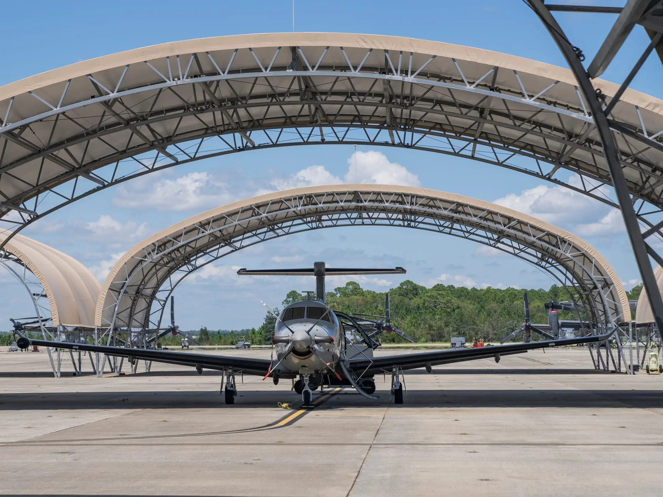 A PC-12 in a dark surveillance fit parked under open-sided sunshades