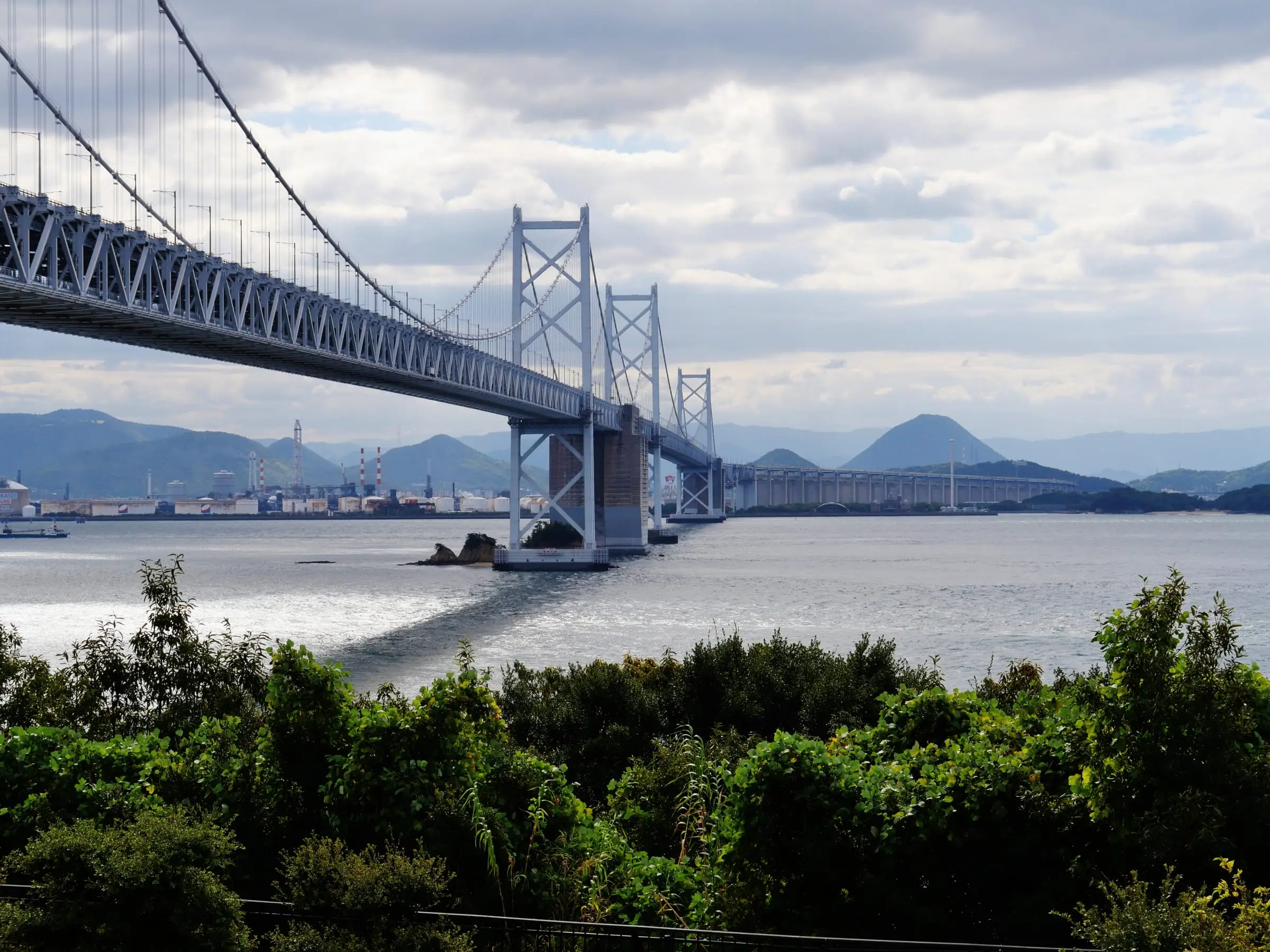 A long span bridge crossing a strait with commercial shipping beneath it