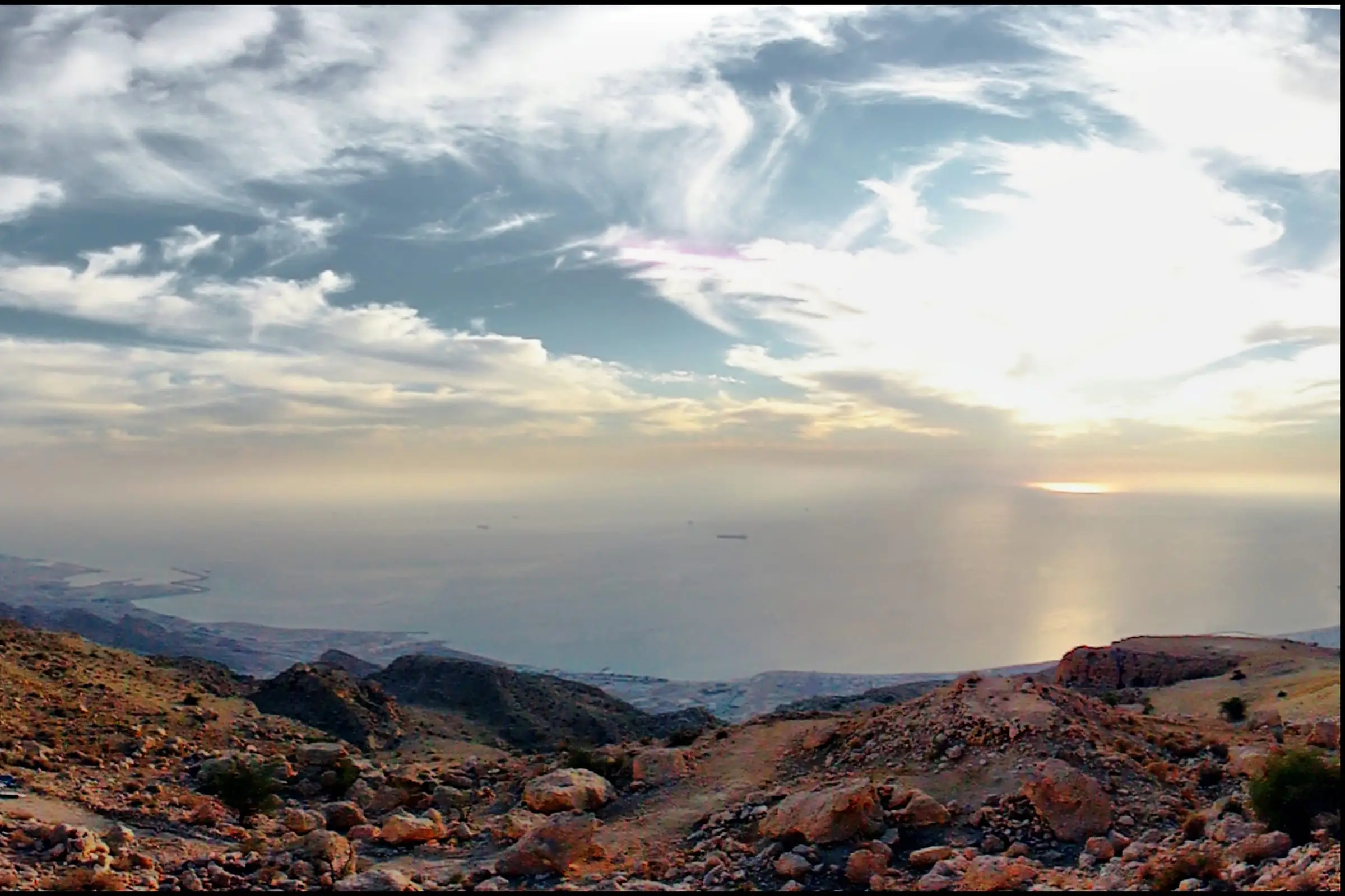 Bare coastal mountains dropping to a wide gulf under low cloud