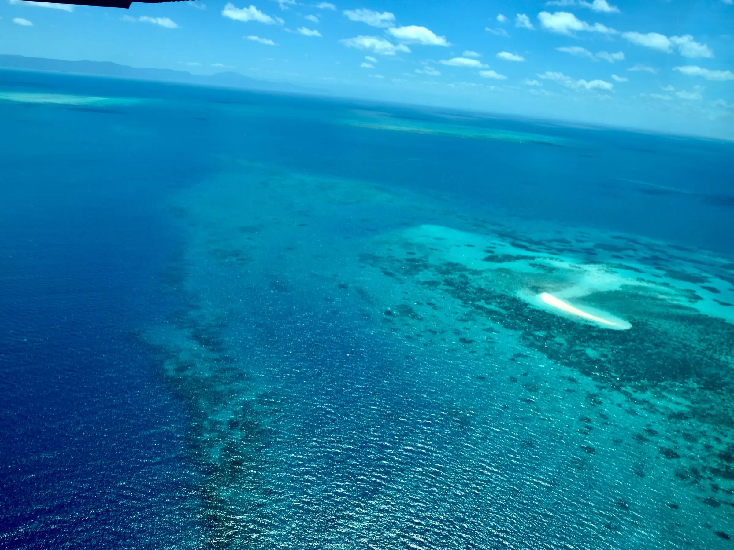 Reef structure visible through clear water across a wide expanse of open sea