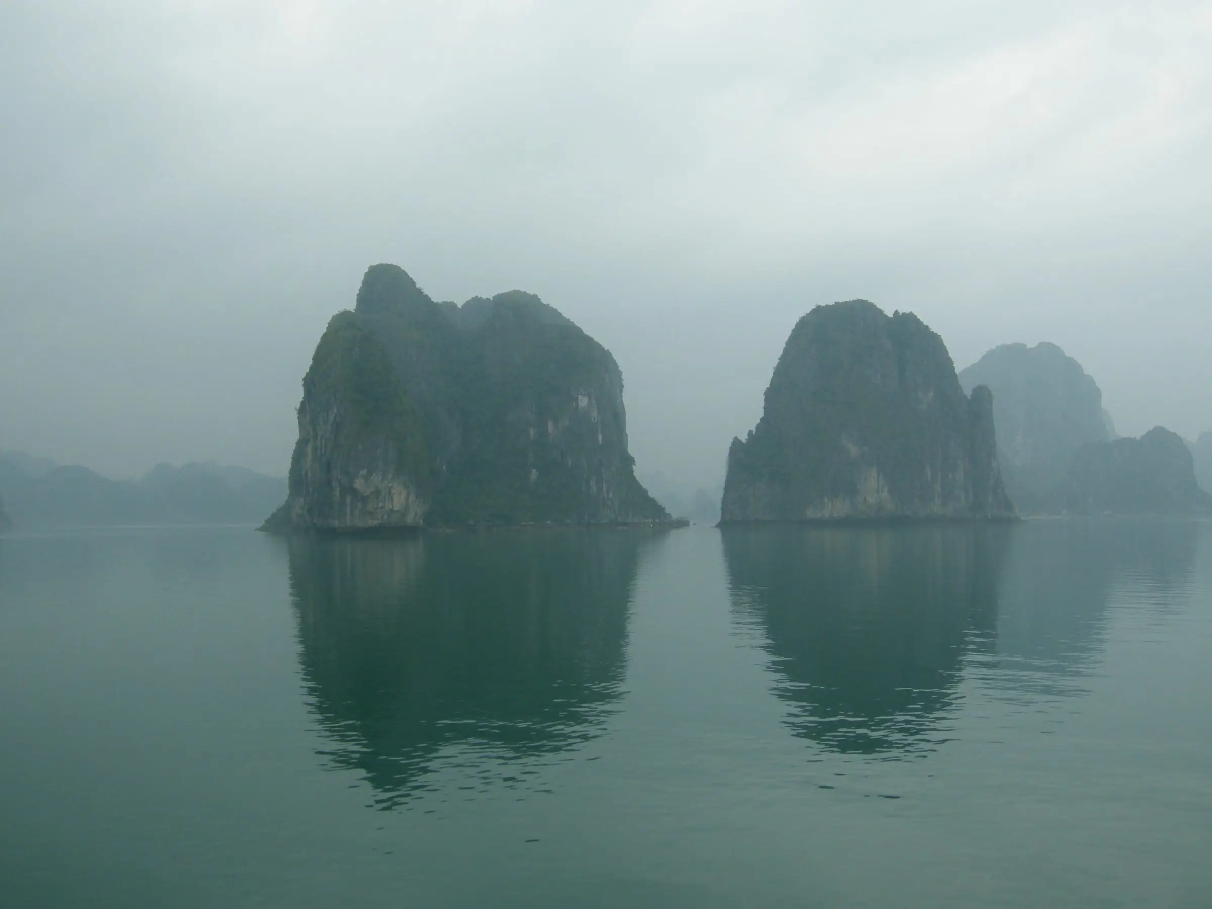 Limestone islands standing in calm water under flat light