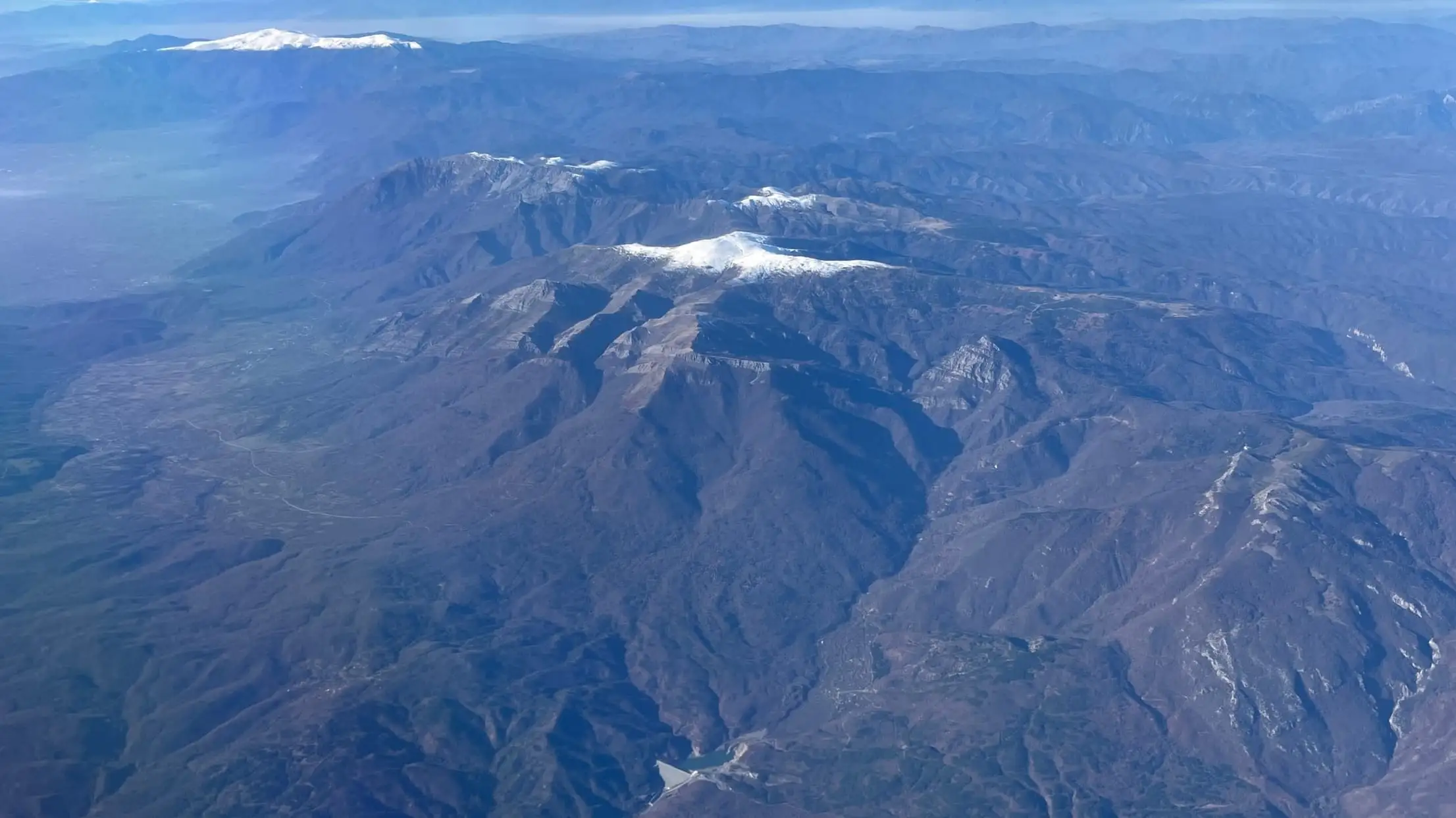 High terrain photographed from altitude, ridgelines receding into haze